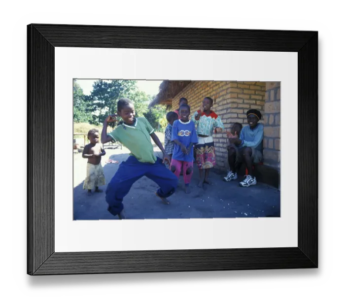 Framed Print : Local children dance happily to music in a village near Kande