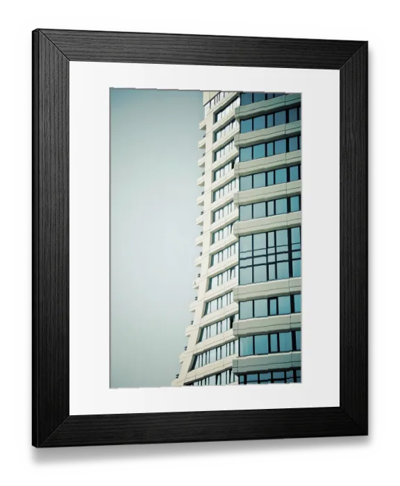 Framed Print : Modern skyscraper with a curved design and blue glass windows against a clear sky