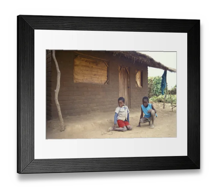 Framed Print : Children in front of a clay hut on the side of the road
