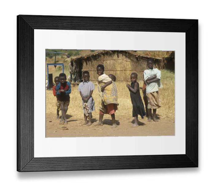 Framed Print : Children in front of a straw hut on the side of the road Framed Print : Children in front of a straw hut on the side of the road
