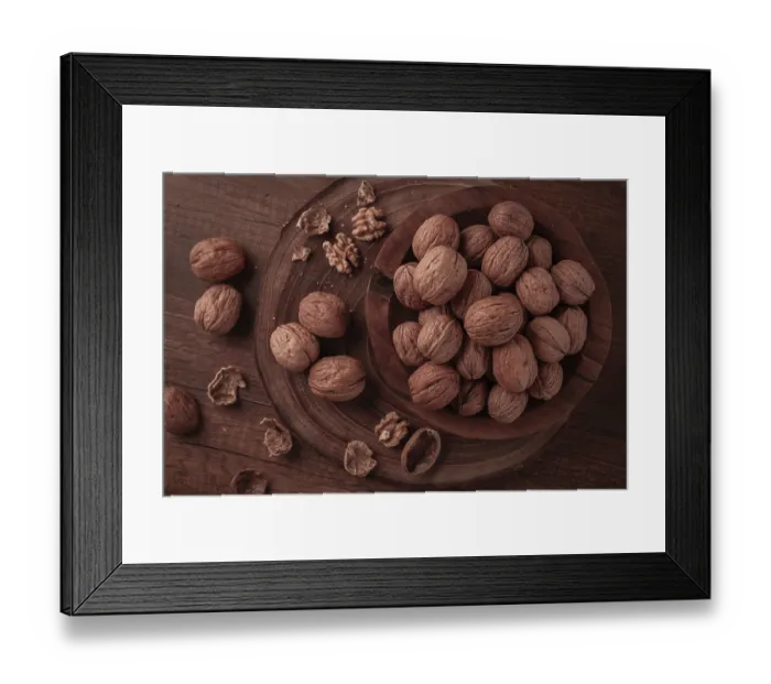 Framed Print : Walnuts are gathered and placed in a wooden bowl on a wooden table