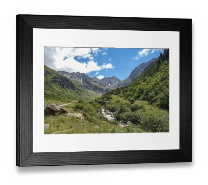 Framed Print : A river winds through a green valley between high mountains
