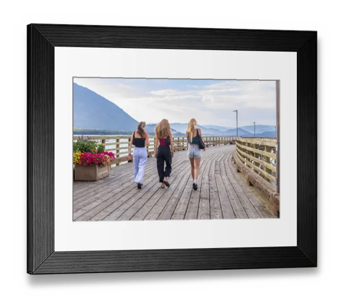 Framed Print : Three young women are enjoying a leisurely stroll along a wooden pier in salmon arm