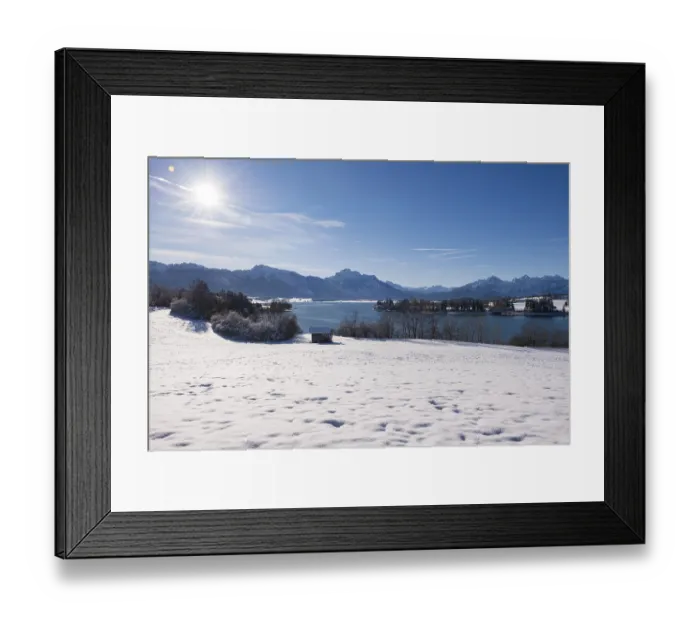 Framed Print : Snowy field with a view of a quiet lake and mountains under a bright sun Framed Print : Snowy field with a view of a quiet lake and mountains under a bright sun