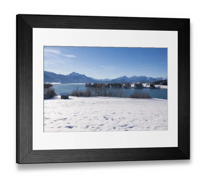 Framed Print : Panorama of a snowy field with lake and mountains under a clear blue sky
