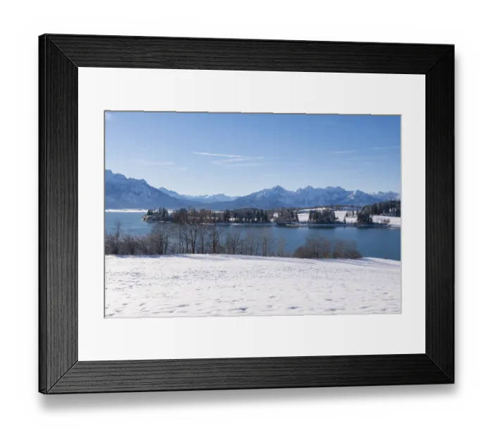Framed Print : Snowy shore with a view of a quiet lake and mountains under a clear sky Framed Print : Snowy shore with a view of a quiet lake and mountains under a clear sky