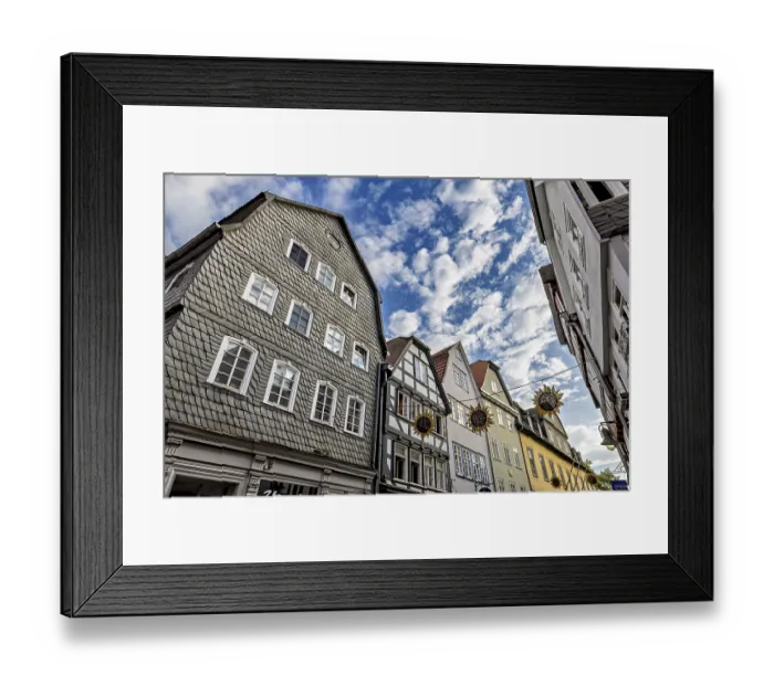 Framed Print : View of half-timbered houses under a vivid blue sky with decorative sun ornaments Framed Print : View of half-timbered houses under a vivid blue sky with decorative sun ornaments