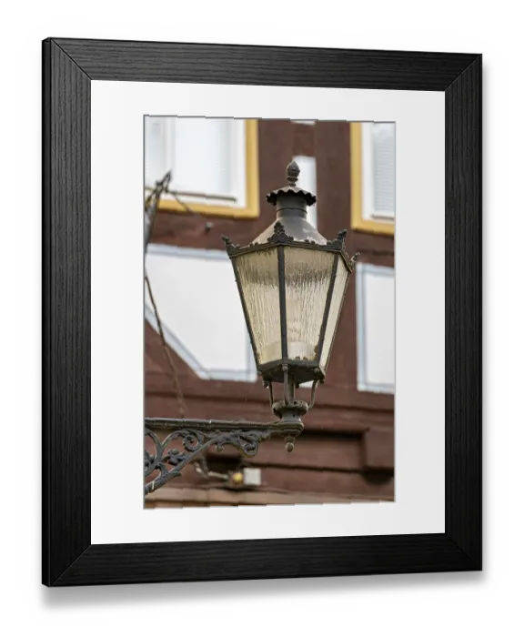 Framed Print : Nostalgic lantern in front of a half-timbered house with windows in a traditional cityscape Framed Print : Nostalgic lantern in front of a half-timbered house with windows in a traditional cityscape