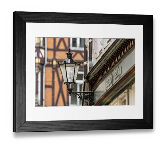 Framed Print : Nostalgic lantern next to a building in front of half-timbered buildings and windows in urban space