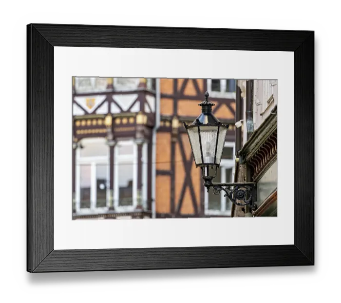 Framed Print : Nostalgic lantern in front of a half-timbered house with traditional architectural elements Framed Print : Nostalgic lantern in front of a half-timbered house with traditional architectural elements