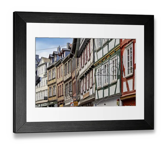 Framed Print : A series of half-timbered houses in various colors that form a lively street scene