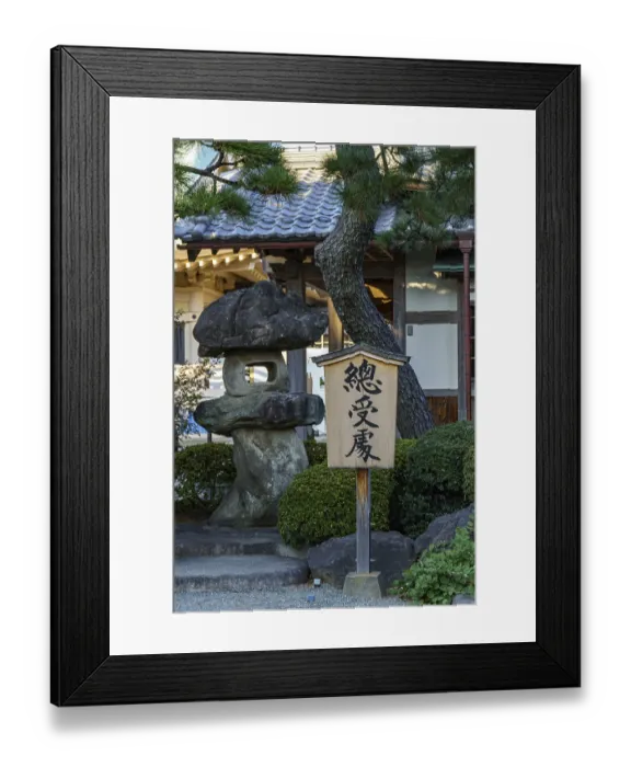 Framed Print : A wooden sign stands next to a large rock in a Japanese garden
