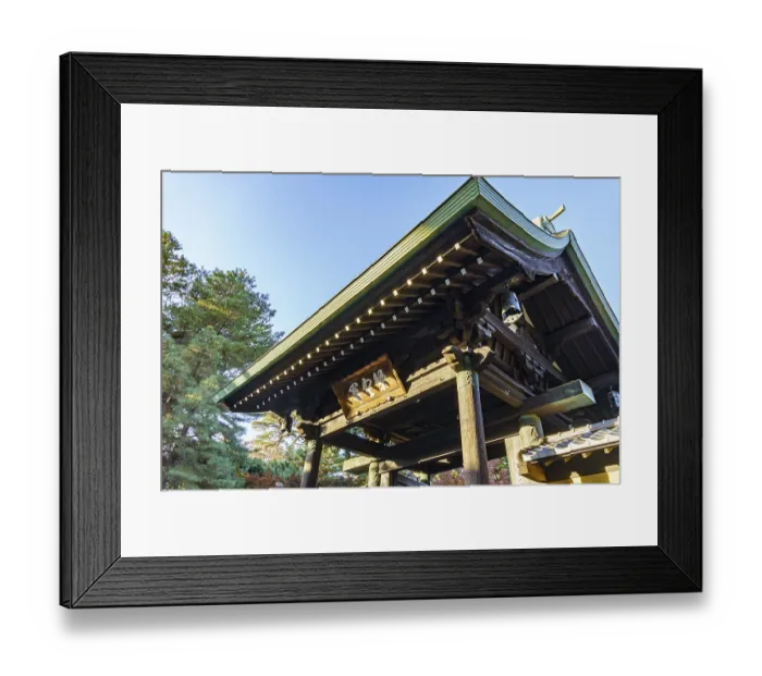 Framed Print : Wooden torii structure at a Japanese temple surrounded by trees and clear skies
