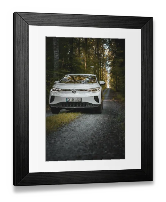 Framed Print : White car on a forest path surrounded by tall trees in morning light