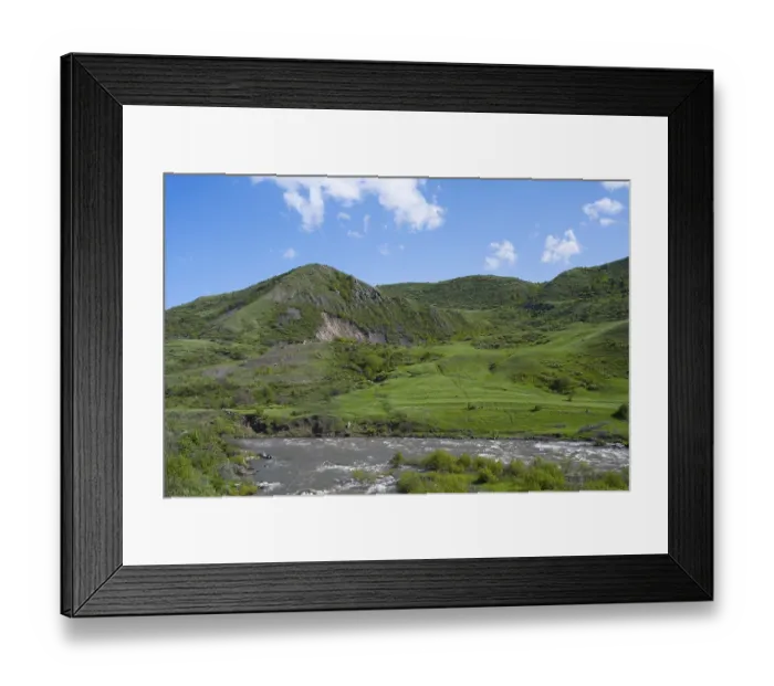 Framed Print : Green hills and a river under a blue sky offer a peaceful landscape