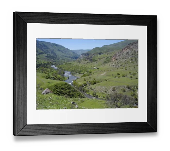 Framed Print : A panoramic view of a green valley with a river surrounded by rolling hills
