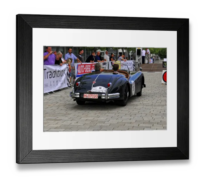 Framed Print : Black classic car from behind with audience and atmosphere of the event