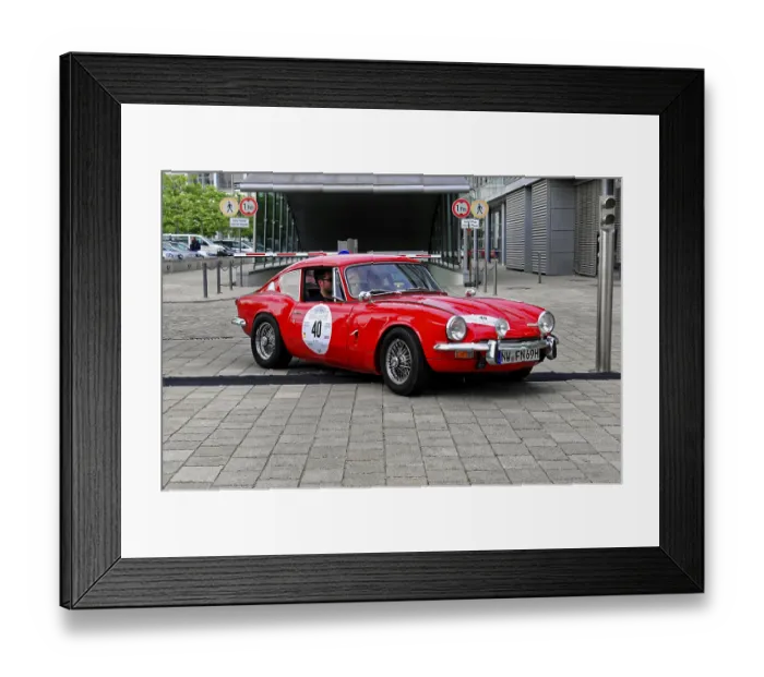 Framed Print : A red Triumph classic car drives on a road Framed Print : A red Triumph classic car drives on a road