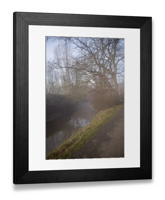 Framed Print : River slowly flowing through a misty winter forest with a winding path