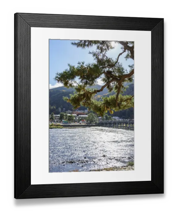 Framed Print : A mighty tree towering over a sparkling river with bridge and mountainous landscape Framed Print : A mighty tree towering over a sparkling river with bridge and mountainous landscape