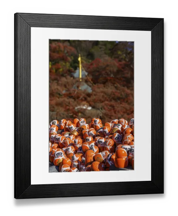 Framed Print : Many Daruma figures in front of an autumn mountain panorama creating a spiritual atmosphere