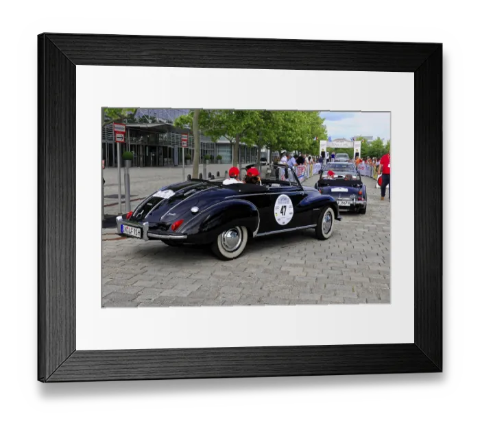 Framed Print : DKW F 93, black vintage convertible driving on a city street with green trees in the background