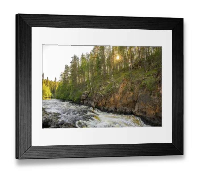 Framed Print : A river flows through a thick forest as the sun shines over the treetops and illuminates the rocks Framed Print : A river flows through a thick forest as the sun shines over the treetops and illuminates the rocks