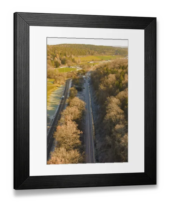 Framed Print : Railway line between trees and a country road in an autumn landscape
