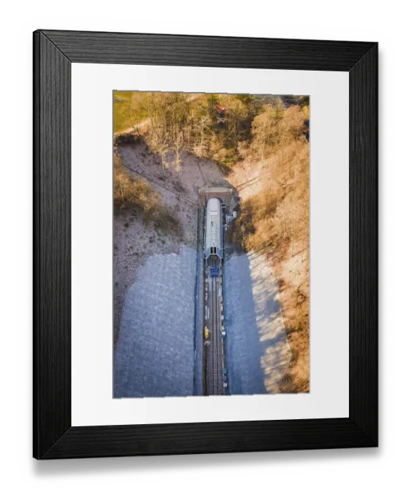 Framed Print : Railway line under a bridge through an autumnal forest