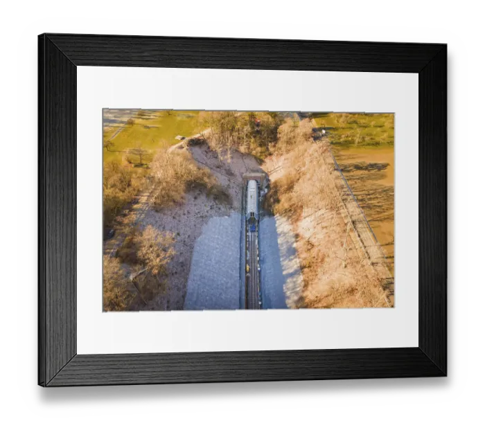 Framed Print : Aerial view of a train line through an autumnal forest and open meadows