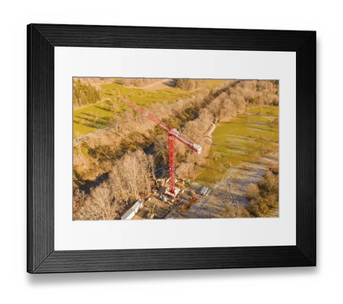 Framed Print : Red crane on construction site in autumn landscape with forests and meadows from a bird's eye view
