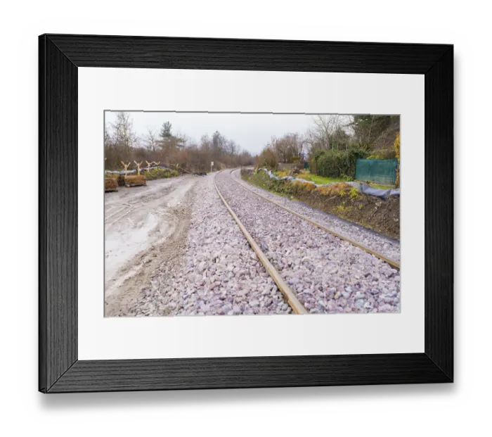 Framed Print : Railway tracks run curvy through a wooded landscape covered with gravel