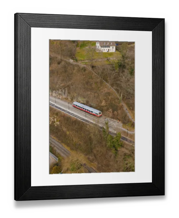 Framed Print : A train travels on a track through wooded hills in a wintry landscape