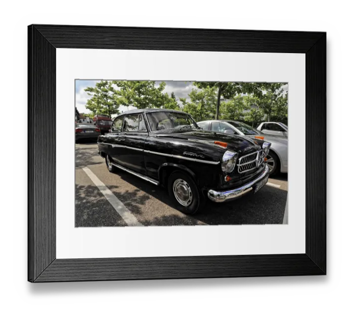 Framed Print : A black classic car is parked in a parking lot surrounded by trees and modern cars