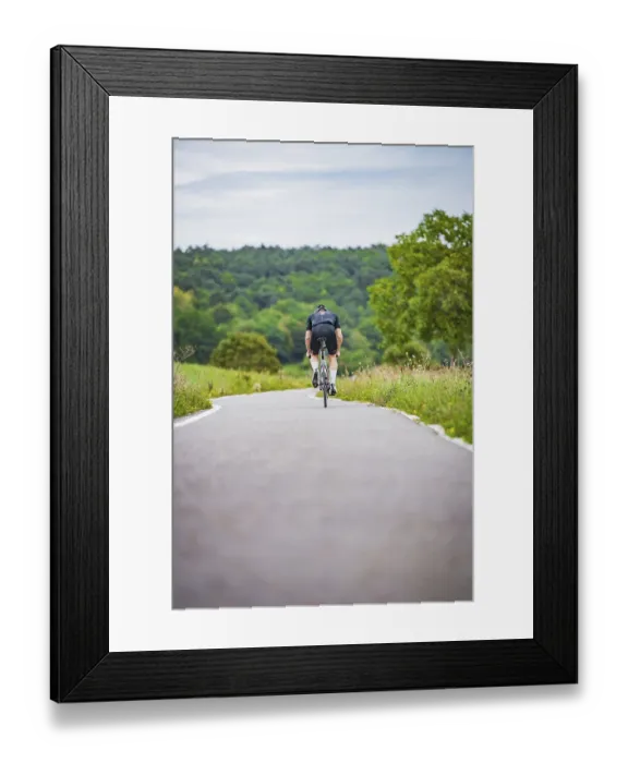 Framed Print : A cyclist rides on a remote road through nature