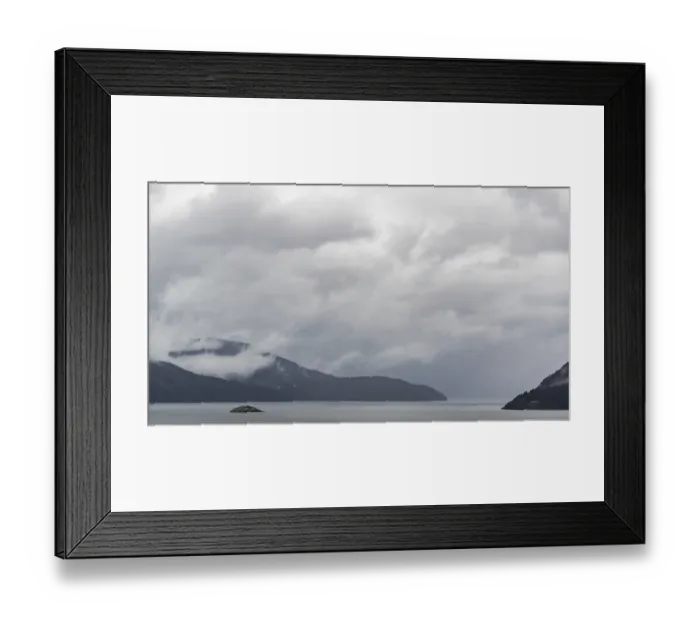 Framed Print : A misty lake with distant mountains and overcast clouds creating a serene