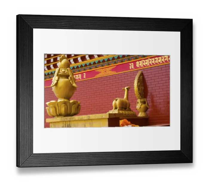 Framed Print : Golden statues on a red brick background with Buddhist symbols and decorations