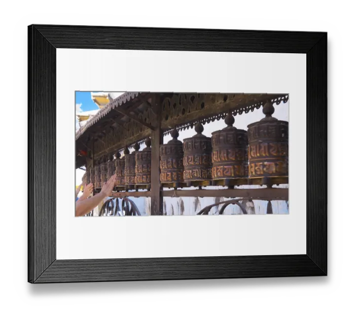 Framed Print : Traditional, artfully designed metal prayer wheels are placed in a row and are touched by hands