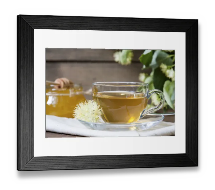 Framed Print : Linden tea in glass cup and jar with honey with linden flowers on a dark wooden background