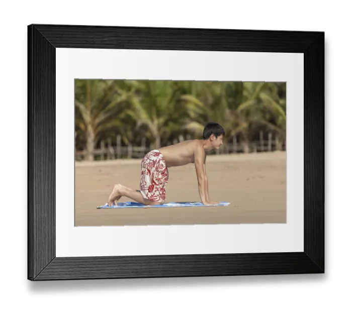 Framed Print : The guy of Asian appearance practices yoga on a beach against palm trees