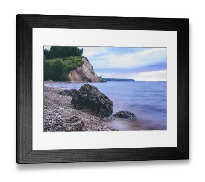 Framed Print : Stone on the riverbank and cliff with birch woodland on background