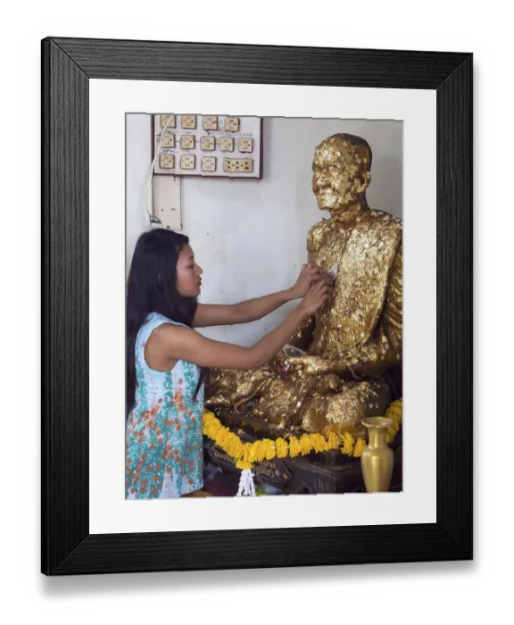 Framed Print : Girl sticks a slice of golden on Buddha statue Framed Print : Girl sticks a slice of golden on Buddha statue