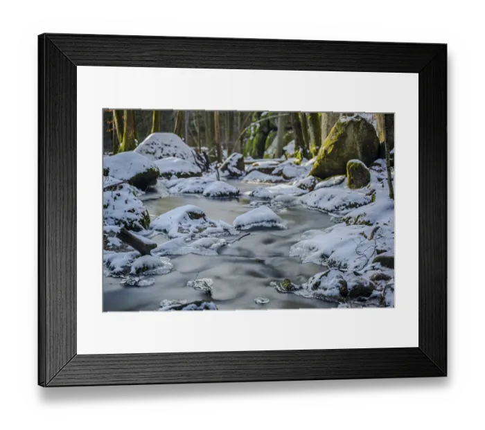 Framed Print : A stream with running water runs through a wooded area