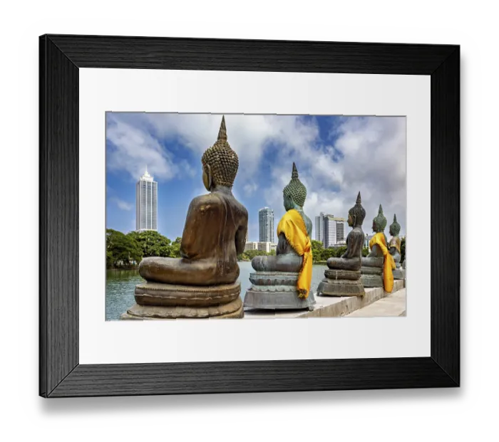 Framed Print : Buddha statues in bronze with yellow cloths in front of skyscrapers and water
