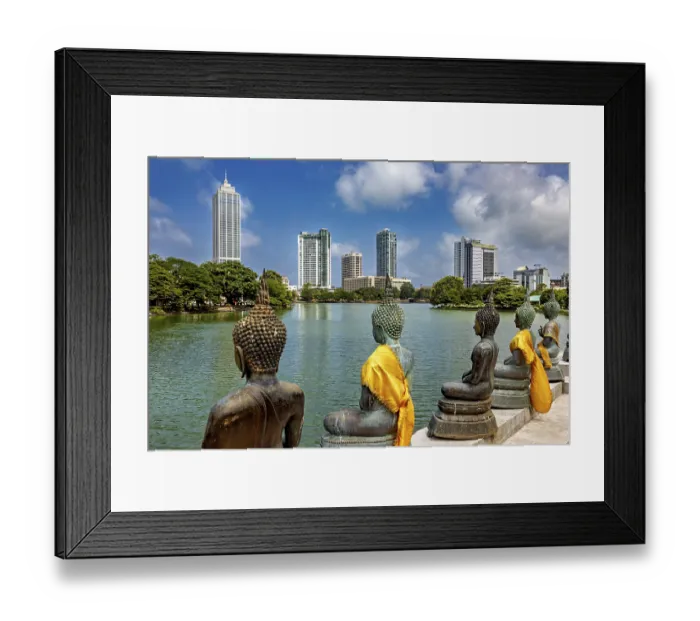 Framed Print : Bronze Buddha statues with yellow cloths look at the skyline of a city