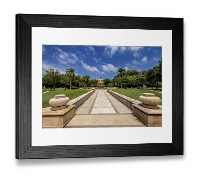 Framed Print : Quiet park with centrally placed Buddha statue and stone path under blue sky