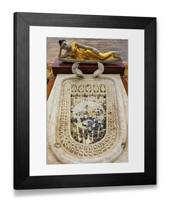 Framed Print : A reclining Buddha statue with gold robes above a carved stone surface filled with coins Framed Print : A reclining Buddha statue with gold robes above a carved stone surface filled with coins