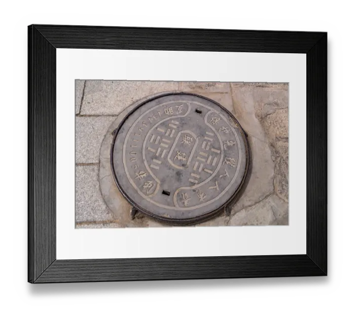 Framed Print : A manhole cover inscribed in Chinese in the courtyard of Kumbum Champa Ling Monastery