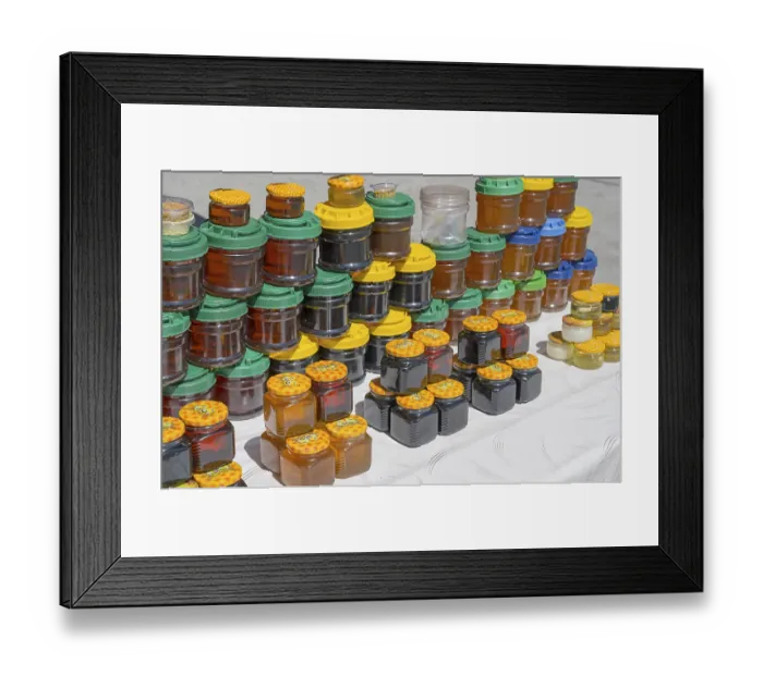 Framed Print : Lots of colorful honey jars with various lids on a market stand