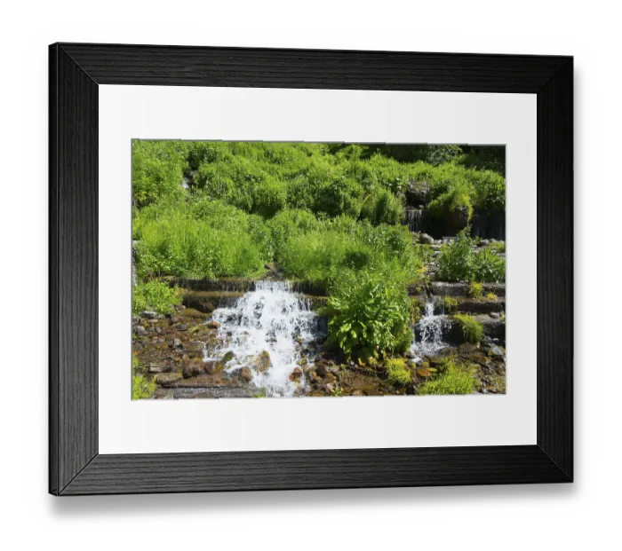 Framed Print : Small waterfall with lush green vegetation and rocky surroundings
